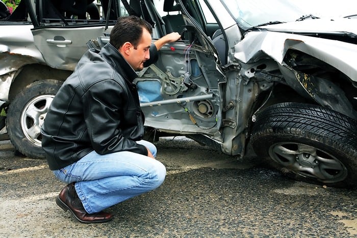 Man inspecting totaled car Man inspecting totaled car