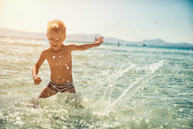child playing in water at beach
